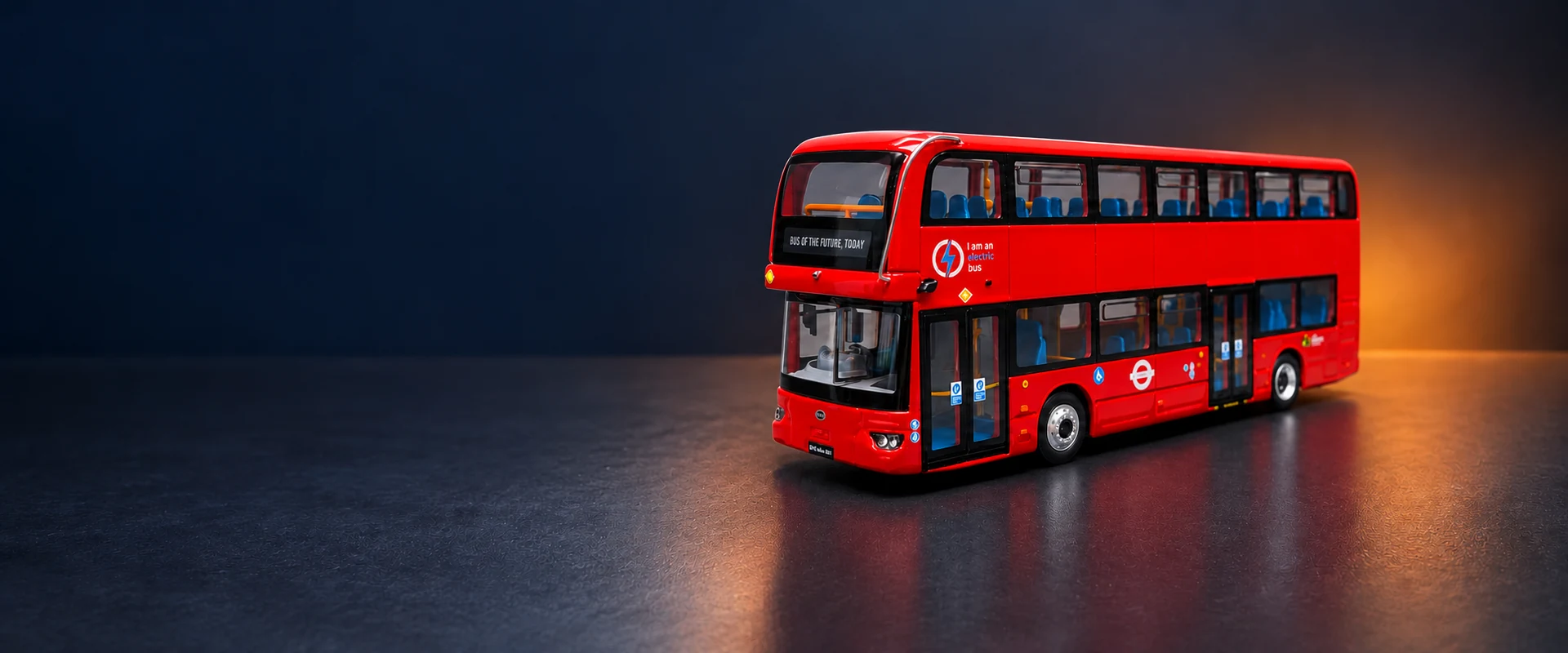 Red BYD double-decker bus miniature against a dark industrial studio background