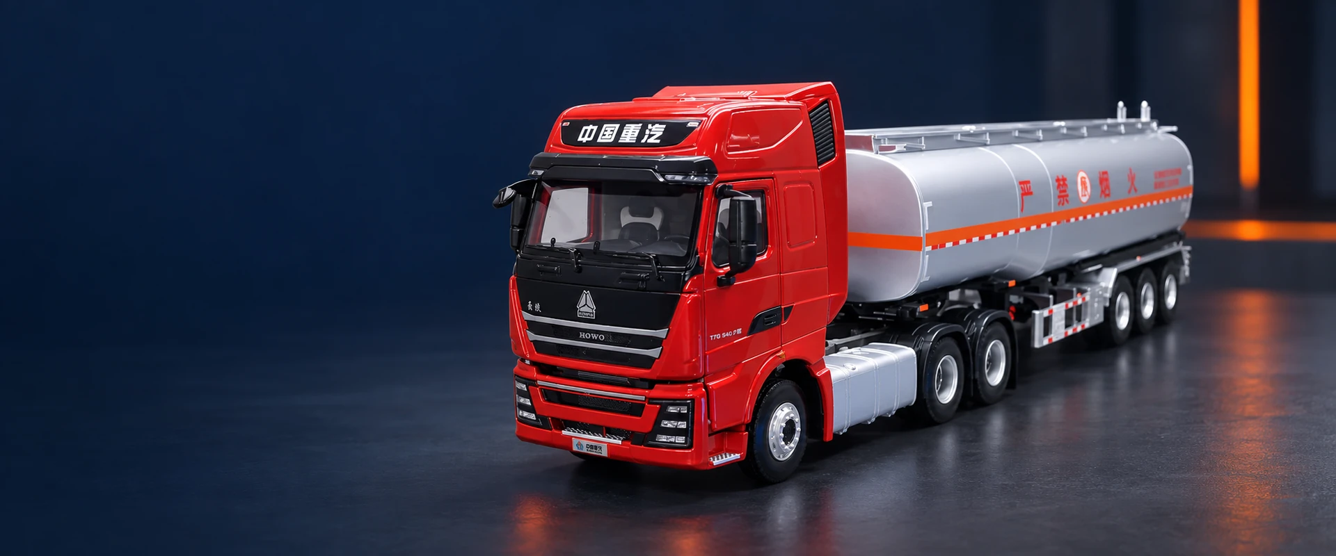 Red HOWO tractor with a silver tanker trailer in a dark studio setting